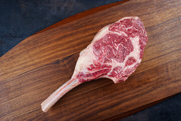 Raw dry aged wagyu tomahawk steak offered as top view on a wooden design board with copy space