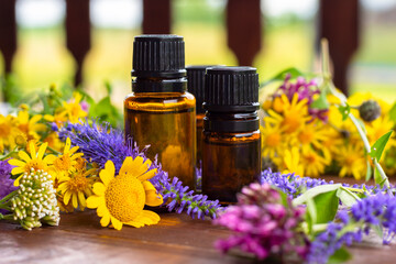 Essential oils. Dark (brown) glass bottles with essential oil and medicinal flowers, herbs on a...