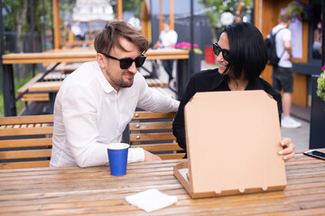 An emotional woman and a man look into an open pizza box