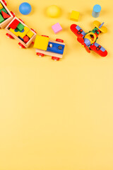 Baby kids toys. Wooden train, airplane, colorful blocks and balls on yellow background. Top view, flat lay