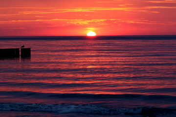 Czerwony zachód słońca nad morzem i czerwona woda.  - obrazy, fototapety, plakaty