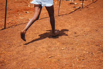 Barefoot running, woman running on red African soil in Kenya. Running in Kenya without shoes. Simple life in Africa.