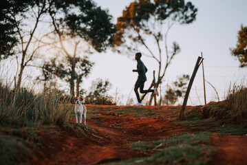 A dog on a red ground, in the background a Kenyan runner who is training. Sports in Africa, marathon training, illustration photo