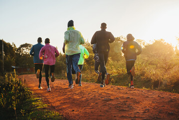 Morning running training. in Kenya. Marathon runners on red soil train in the light of the rising sun. Motivation to move. Endurance running, athletics and sports
