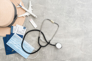 Travel and vacation concept. Trip accessories and items. Airplane toy over passport with airplane tickets and face masks. Top view flat lay with copy space.