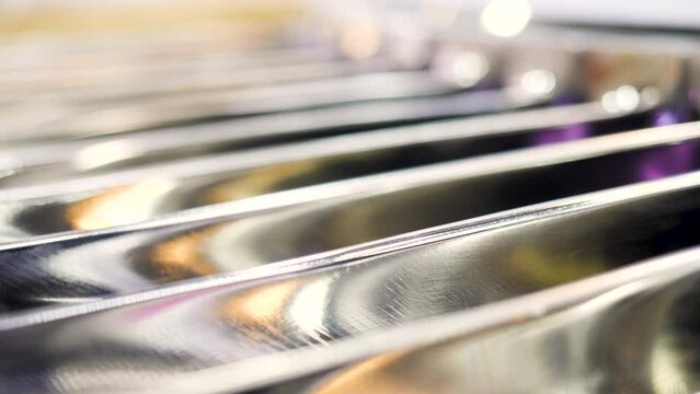 Close up of metal blurred parallel bars with blinking small light bulbs. Media. Industrial background with a part of machine.