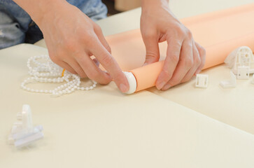 Assembly of roller blinds. Women's hands are assembling roller blinds, close-up.