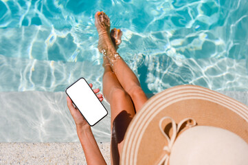 A girl by the pool holds a smartphone in her hand with a blank white display. Top view, mock up.