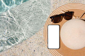 Smartphone with a blank white display on a straw hat by the pool in the hotel. Top view, mock up.