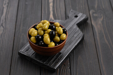 Black and green olives on a dark wooden rustic background.