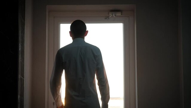 A thin man with cancer walks along the corridor of the hospital to the balcony to breathe fresh air