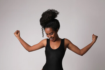 Happy African American young woman posing indoor shows her arms. Mock-up.