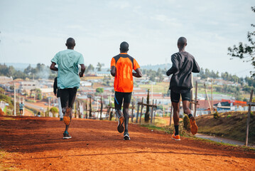 Morning running training. in Kenya. Marathon runners on red soil train in the light of the rising sun. Motivation to move. Endurance running, athletics and sports