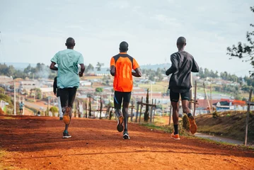 Gordijnen Morning running training. in Kenya. Marathon runners on red soil train in the light of the rising sun. Motivation to move. Endurance running, athletics and sports © kovop58