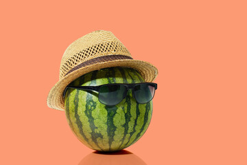 Watermelon with sunglasses and straw hat on orange pastel background