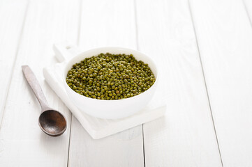 Mung bean in a white plate on a white wooden background