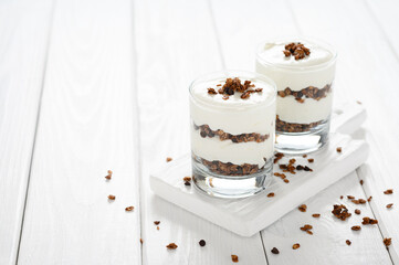 Dessert with mascarpone cheese and granola on a white wooden background.