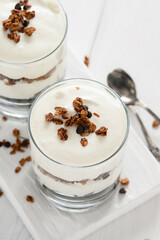 Dessert with mascarpone cheese and granola on a white wooden background.