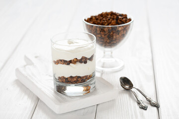 Dessert with mascarpone cheese and granola on a white wooden background.