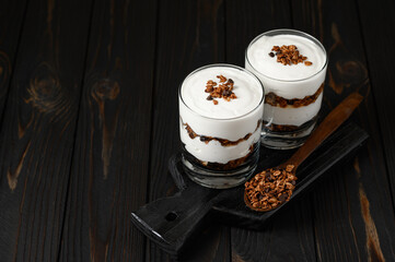 Layered dessert with granola on a wooden dark wooden background.