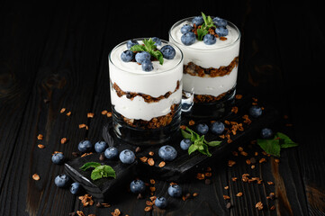 Dessert with mascarpone cheese, fresh blueberries and muesli in a glass on a rustic background.