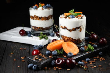 Homemade layered dessert with fresh apricot, blueberry, cherry, cream cheese or yogurt, granola.