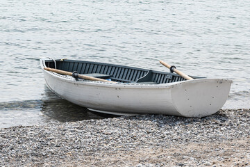 White painted wooden row boat with oars in the oar locks drawn up on the sand of Toronto's Balmy Beach at midday. © Michael Connor Photo