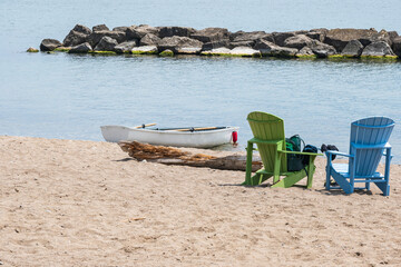 White painted wooden row boat with oars in the oar locks drawn up on the sand of Toronto's Balmy Beach at midday.