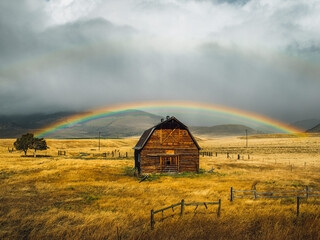 Beautiful barn cabin under a fall rainbow in a golden field