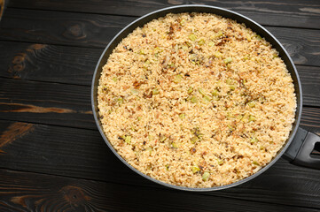 Fried rice with onions and zucchini in a pan on a rustic wooden background.