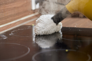 Cleaning of induction cooker with steam cleaner.
