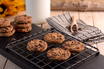 Delicious chocolate cookies on a black rack with milk bottle
