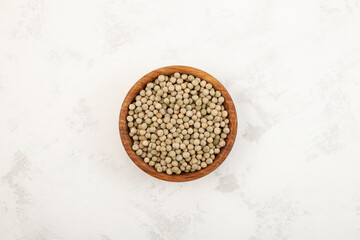 Dried green peas in wooden bowl on light grey textured background, top view. Green seeds from the pods of Pisum sativum