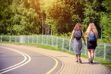 Two girlfriends walk along a path in the Park
