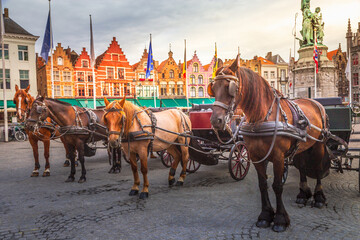 Bruges market square with flemish architecture and horse carriages, Belgium