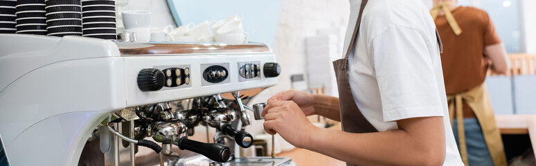 Cropped view of african american barista making coffee in confectionery, banner.