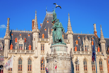 Fototapeta na wymiar Pigeon flying above Bruges market square, flemish architecture