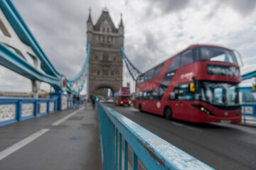 London Bridge on a cloudy day with traditional red bus passing in the background.