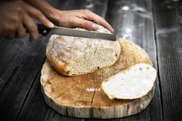 Traditional leavened sourdough bread cut into slice on a rustic wooden table. Healthy food...