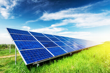 Solar panel on blue sky background. Green grass and cloudy sky. Alternative energy concept