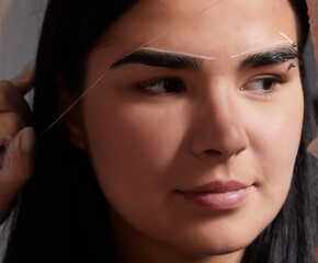 Beautiful young girl got correction of eyebrows in a beauty salon.