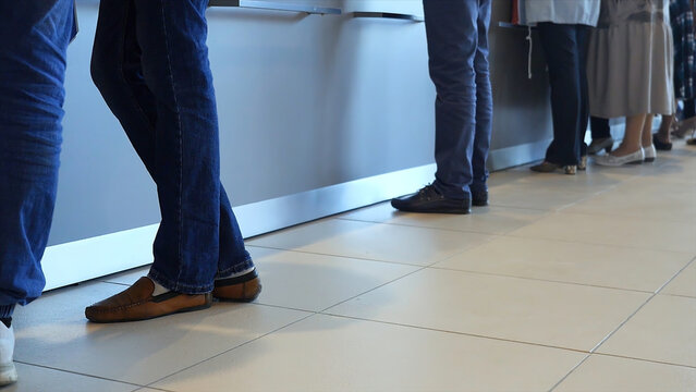 View of legs of customers standing n the modern office, getting served in the bank. Media. People are queuing for service in the department of a bank.
