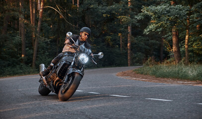 Blurred Motion A young man biker in a helmet quickly rides at high speed on a forest road, in motion