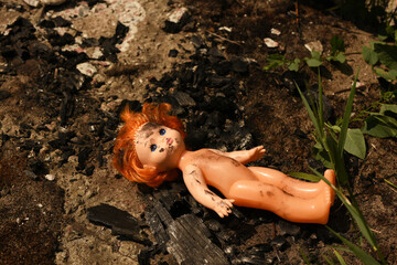 A plastic doll, dirty with soot, in front of the remains of a burnt-out house caused by a bombing raid. © TetiBond