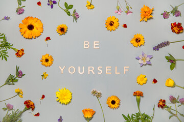 Be yourself motivating picture, words from wooden letters on light green background surrounded by fresh flowers, two words motivating image, motivating postcard