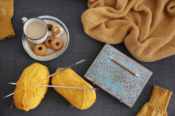 Knitting yarn knitting needles yellow blanket cup of coffee with cookies and notebook, cozy sweet...