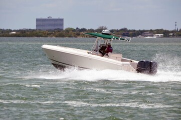 Open sports fishing boat speeding on the Florida `intra-Coastal Waterway off of `Miami Beach