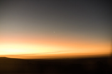 sunset in the mountains with a crescent moon