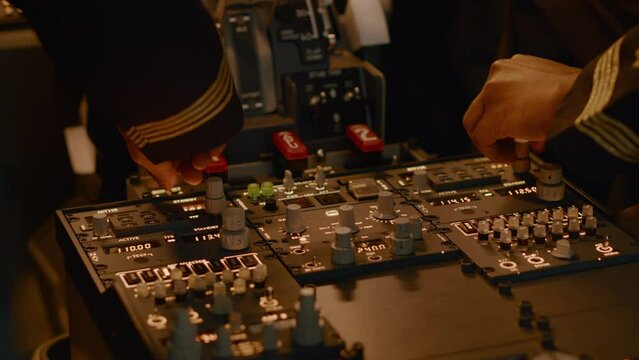 Captain and copilot pushing dashboard buttons to start engine, using airline navigation command to fly airplane. Taking off using control panel switch and handle, flying aircraft. Close up.