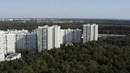 Aerial view of residential houses neighborhood in suburban area of the city. Action. Tightly packed homes surrounded by green trees park or small forest, housing development.